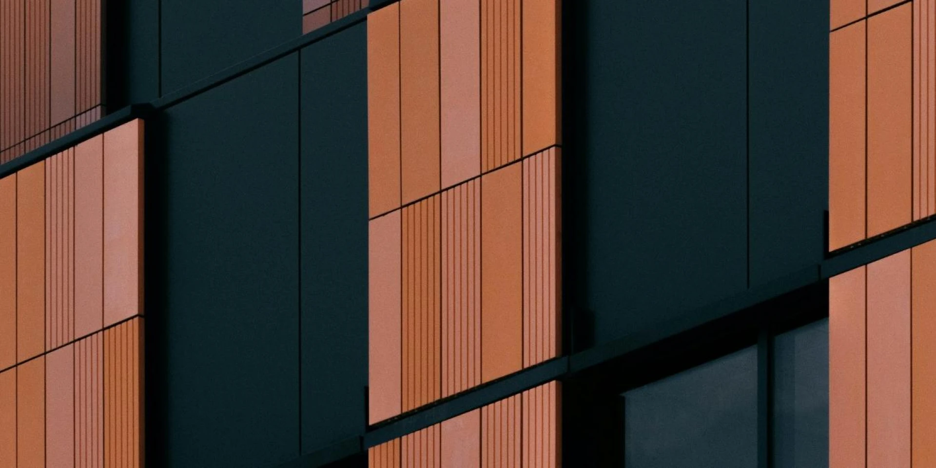 Close-up of a building facade with orange and black panels, showing a modern architectural design